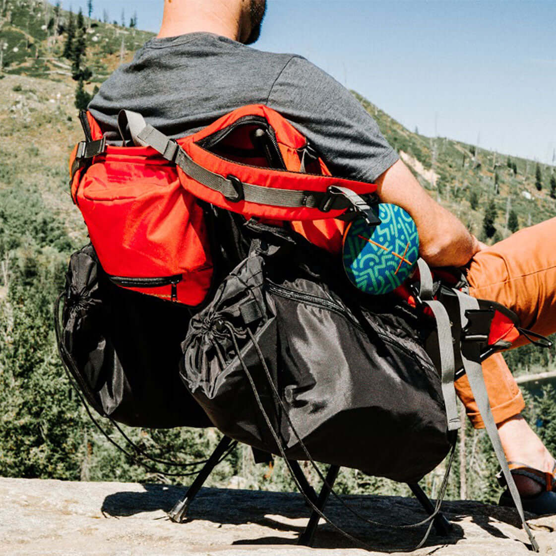 Person relaxing in a chair with Trailform Switch Bags attached, enjoying the outdoors with a stunning mountain view.