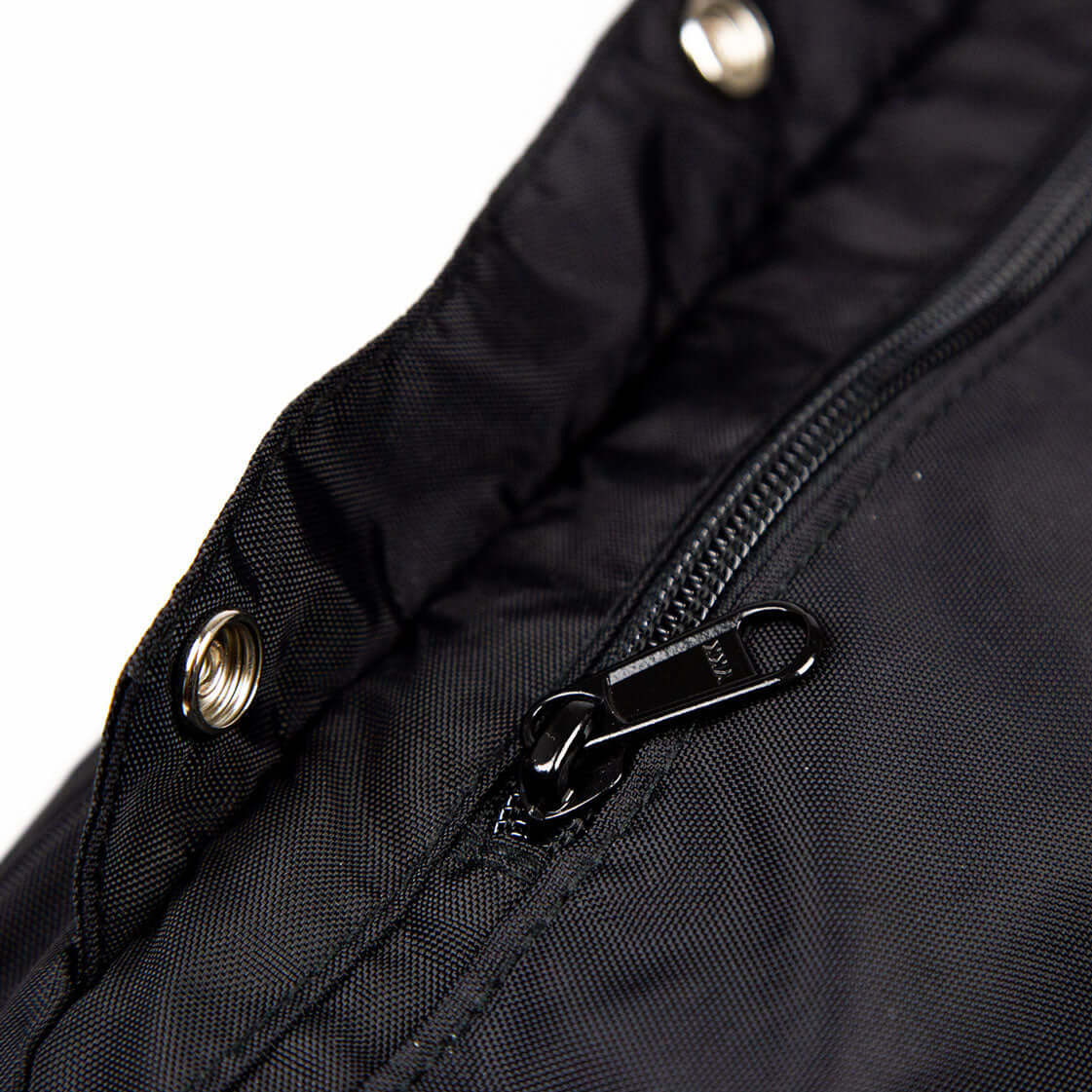 Close-up of the sleek zipper and snap button on a Trailform Switch Bag, showcasing its durable black fabric design.